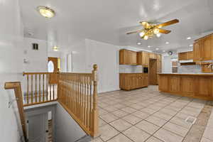Kitchen with light tile patterned floors, wood finish cabinets, recessed lighting, a peninsula, and ceiling fan
