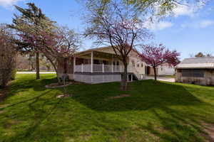 Back of house featuring a yard, a porch, and a metal roof