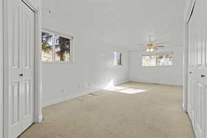 Unfurnished bedroom with a closet, multiple windows, and light colored carpet