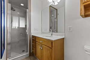 Full bathroom with vanity, a marble finish shower, and light tile patterned floors