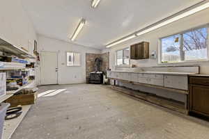 Kitchen with dark wood finish cabinets, a wood stove, and vaulted ceiling