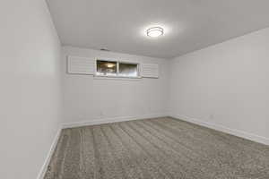 Empty room featuring carpet and a textured ceiling