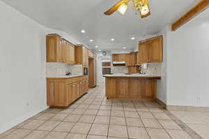 Kitchen featuring a peninsula, light countertops, a ceiling fan, recessed lighting, and wood finish cabinetry