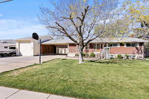Ranch-style house featuring concrete driveway, an attached garage, a porch, a front lawn, and brick siding