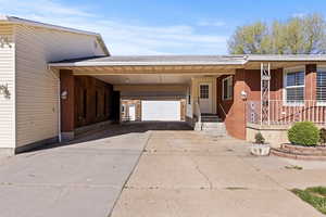 View of front of house with a carport, driveway, a porch, brick siding, and a shingled roof