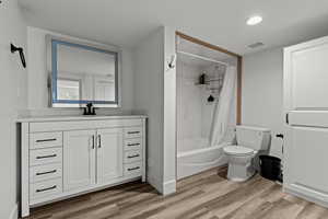 Bathroom featuring vanity, light wood-style floors, shower / bath combo, and recessed lighting