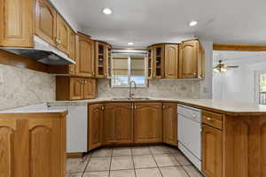 Kitchen featuring glass insert cabinets, tasteful backsplash, wood finish cabinets, light countertops, and recessed lighting