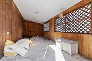 Miscellaneous room featuring lofted ceiling and wood walls