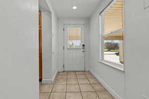 Doorway to outside with tile patterned flooring and baseboards
