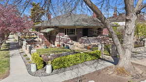 View of front of home featuring a chimney, brick siding, and a shingled roof