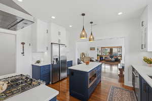 Open concept kitchen with large island, gas range, and wood floors