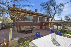 Back of property featuring a chimney, brick siding, a patio area, and an outdoor lounge area