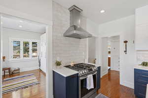 Open concept kitchen with large island, gas range, and wood floors