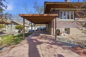 View of patio featuring driveway, a storage unit, and a carport