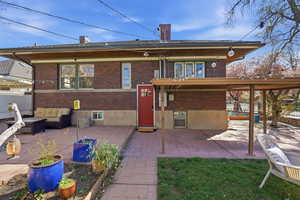Back of house with a chimney, brick siding, a patio, and outdoor lounge area