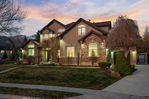 View of front of property featuring stone siding, a lawn, stucco siding, and concrete driveway