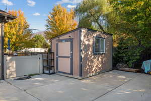 View of shed with a fenced backyard and a gate