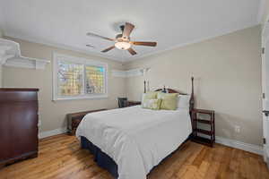 Bedroom with wood-type flooring, a ceiling fan, crown molding, and a textured ceiling