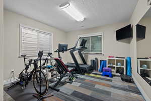 Exercise area with a textured ceiling and baseboards