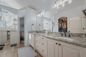 Bathroom with double vanity, a walk in closet, and parquet flooring