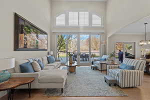 Living area featuring a high ceiling, light wood-type flooring, and a chandelier