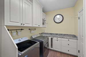 Laundry area with cabinet space, dark wood-style flooring, and separate washer and dryer