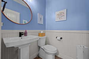 Half bath featuring wainscoting and wood finished floors