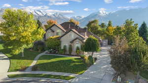 French country style house with stucco siding, stone siding, a front yard, a mountain view, and an outdoor structure