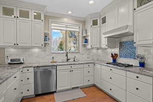 Kitchen featuring glass fronted cabinets, white cabinetry, stainless steel appliances, open shelves, and ornamental molding