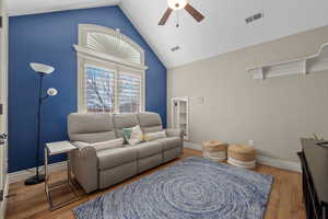 Living area featuring a ceiling fan, light wood-style flooring, and a high ceiling