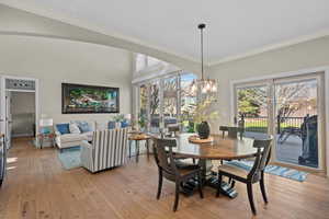 Dining area with light wood finished floors, hanging lights, crown molding, and healthy amount of natural light