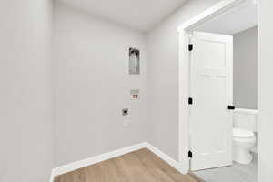 Laundry area with hookup for a washing machine, electric dryer hookup, and light wood-type flooring