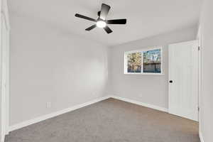 Empty room with light colored carpet and a ceiling fan