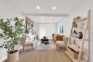 Living area featuring recessed lighting, light wood-style floors, a fireplace, and beam ceiling