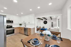 Dual tone kitchen featuring stainless steel appliances, recessed lighting, decorative backsplash, two tone color scheme, and light wood-type flooring