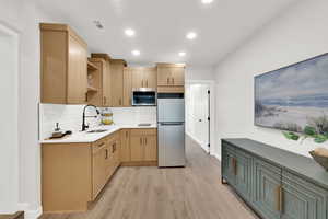 Kitchen featuring stainless steel appliances, light wood-style floors, light wood finish cabinetry, light stone counters, and open shelves