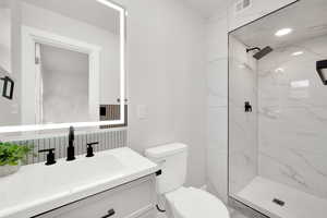Bathroom with vanity and a marble finish shower