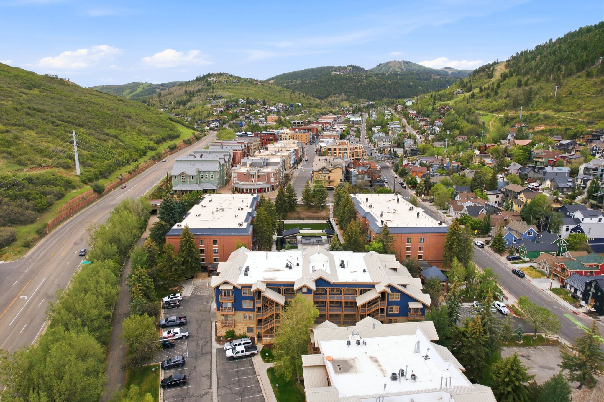 Aerial perspective showcasing multiple residential and commercial buildings nestled among lush green hills