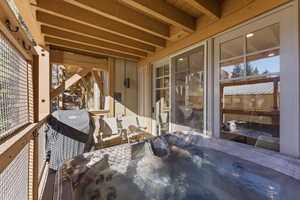 Wooden terrace featuring a hot tub and a grill