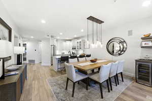 Dining room with beverage cooler, light wood-style floors, and recessed lighting