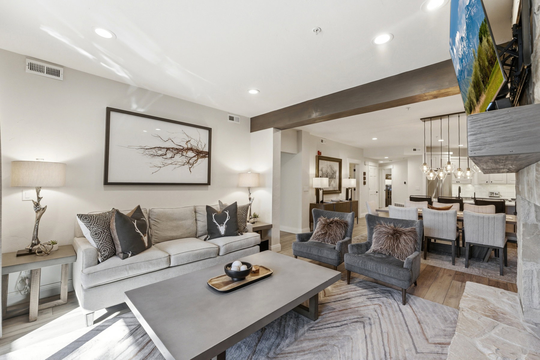 Living area with light wood-style flooring, beamed ceiling, and hanging lights