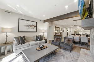 Living area with light wood-style flooring, beamed ceiling, and hanging lights
