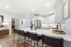 Kitchen featuring a kitchen bar, a peninsula, light wood finished floors, high quality fridge, and decorative backsplash