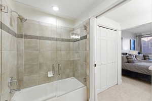 Bathroom featuring connected bathroom, a closet, enclosed tub / shower combo, and carpet flooring