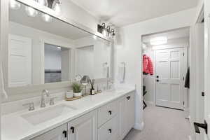 Full bath with double vanity and light carpet