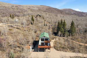 View from above of property with a mountain backdrop and a forest