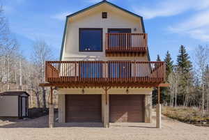 View of front of home with a balcony, a garage, driveway, and a shed