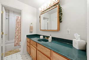 Full bathroom with vanity, shower / bath combo with shower curtain, and light flooring