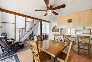 Dining space featuring a wood stove, light wood-style flooring, and ceiling fan