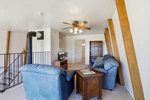Living area with ceiling fan and light colored carpet